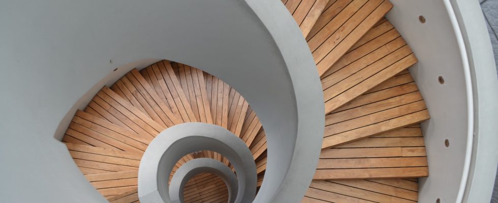 brown wooden spiral staircase with white wall